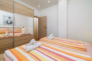 A hotel room with a bed, a mirror, a wooden door, and a light fixture. - Quiet apartment with pool, terrace and parking in Crikvenica (Crikvenica)