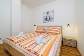 Un lit double avec une literie à rayures, une tête de lit en bois et deux tables de chevet avec des lampes.
