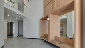A modern interior with a high ceiling, a mezzanine level, and a large mirror reflecting the room. - RentPlanet - Apartament Starowiejska (Gdańsk)