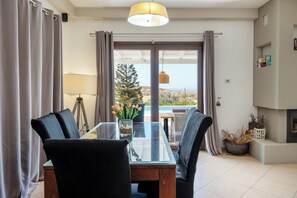 Ett modernt matområde med ett glasbord, svarta stolar och utsikt över omgivningen.