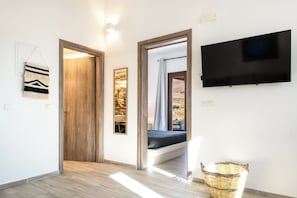 A hallway with a wooden door, a wall-mounted TV, and a wicker basket.