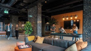 A modern lounge area with a pool table, comfortable seating, and a large plant. - Student Only Brent Cross (London)
