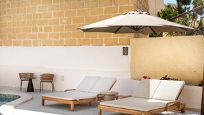 A poolside area with lounge chairs, a table, and an umbrella. - Casa Elana Holiday Gozitan Home (Xaghra)