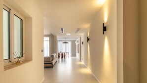 A modern hotel corridor with a sofa, dining table, and pendant lighting. - Casa Elana Holiday Gozitan Home (Xaghra)