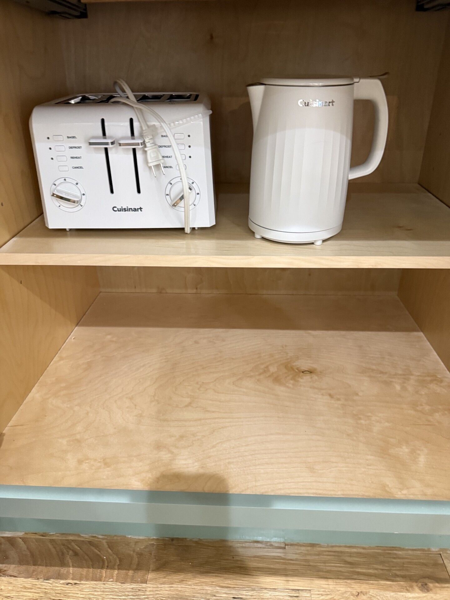 Een kitchenette met een witte Cuisinart broodrooster en een witte Cuisinart koffiezetapparaat op een houten plank.