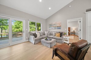 A spacious living room with a grey sectional sofa, a leather armchair, and a coffee table.
