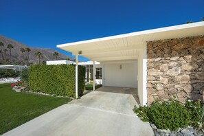 A modern house with a stone exterior, a covered porch, and a well-maintained lawn. - Beautiful Canyon View Estates Condo with amazing views (Palm Springs)