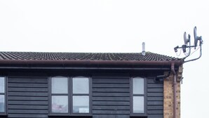 A two-story building with a black exterior, a brick base, and a black door with a small step leading up to it.