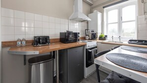 A compact kitchen with a stove, microwave, toaster, and sink.
