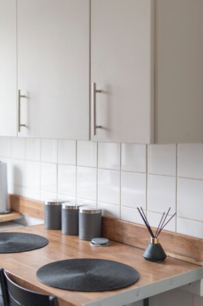 A kitchen with white cabinets, a wooden countertop, and three spice containers.