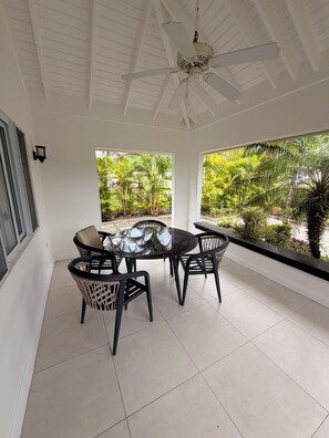 A covered patio with a ceiling fan, a round glass table, and black chairs. - 3-bedroom house in Ocho Rios, Richmond Estate with private pool (Plantation Village)