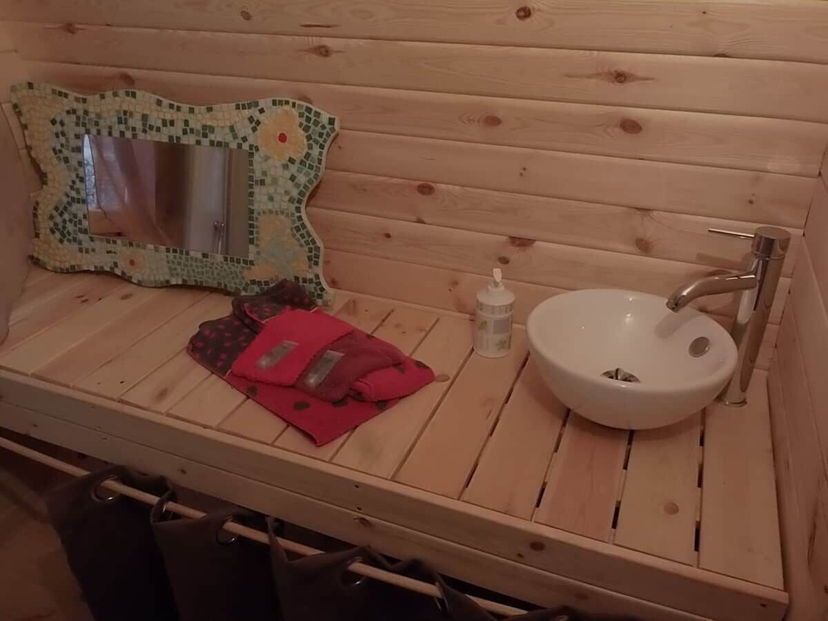 Un tocador de madera con lavamanos, espejo y toalla roja.