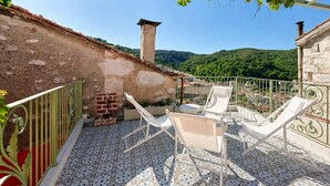Eine Terrasse mit weißen Lounge-Stühlen, einem Backofen aus Ziegeln und einem gefliesten Boden.