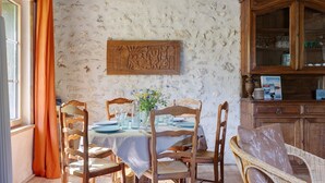 Een eetgedeelte met een tafel voor vier personen, houten stoelen, een buffetkast en een wanddecoratie.