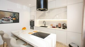 A modern kitchen with a central island, a black range hood, and a marble backsplash.