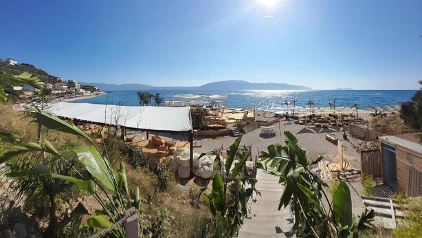 A coastal view with a beach, a white tent, and a clear sky.