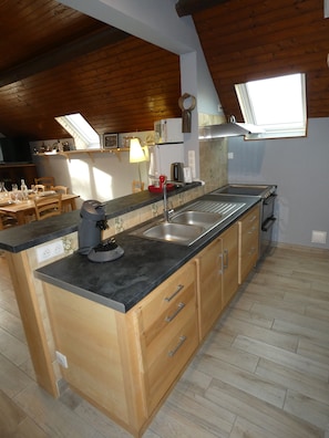 A kitchen with wooden cabinets, a black countertop, a sink, and a window above the sink. - Holiday Home “L’oustal De Préchac” with Mountain View, Private Terrace and Wi-Fi (Préchac)