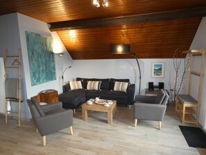A cozy living room with a wooden ceiling, a black sectional sofa, two armchairs, a coffee table, and a wooden floor. - Holiday Home “L’oustal De Préchac” with Mountain View, Private Terrace and Wi-Fi (Préchac)