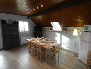 Een eetruimte met een houten tafel voor zes personen, een televisie en een koelkast.