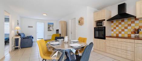 A modern kitchen with a dining area, featuring a round table, chairs, and built-in appliances.