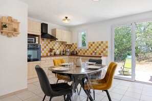 Uma cozinha moderna com área de refeições, apresentando um painel de backsplash xadrez, armários de madeira e uma janela grande.