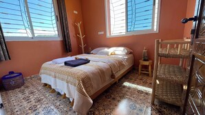 A room with a bed, a small table, a chair, and a window with blinds. - Tremendous 4-bedroom bed & breakfast in tranquil Imi Ouaddar (Imi Ouaddar)