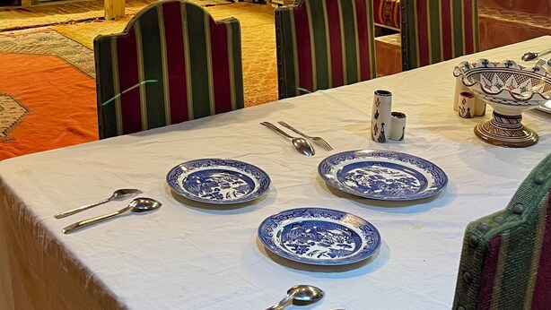 A dining area with a table set for four, featuring blue and white patterned plates, silver cutlery, and striped chairs. - Tremendous 4-bedroom bed & breakfast in tranquil Imi Ouaddar (Imi Ouaddar)