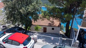 Un edificio frente al mar con tejado de baldosas, coches aparcados y un muro de piedra.