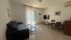 Una sala de estar con sofá, mesa de centro, televisor y comedor con sillas.