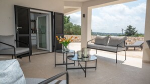 Ein Balkon mit einer Couch, Stühlen, einem Tisch und einem Blumenstrauß.