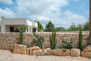 A modern building with a stone wall and cacti in front. - Villa Euphorbia by Rentbeat (Ostuni)