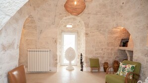 Ein Zimmer mit Steinwänden, einem weißen Heizkörper, einem runden Tisch und zwei Stühlen.