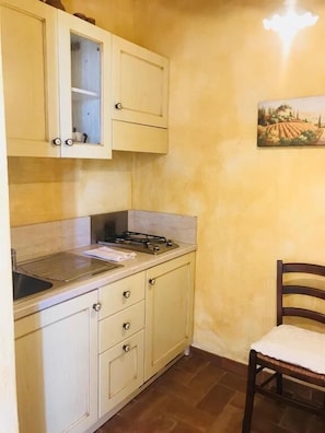 A compact kitchen with a gas stove, a sink, and cabinets. - AGRITURISMO IL CARDO (Soiano del Lago)