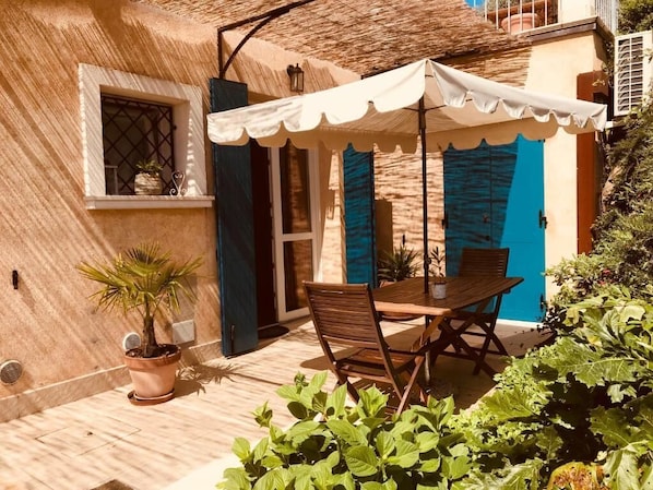 A patio with a table and chairs, a potted plant, and a blue door. - AGRITURISMO IL CARDO (Soiano del Lago)
