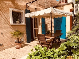 Un patio con una mesa, sillas, una planta en maceta y una puerta azul.