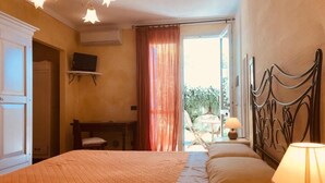 A bedroom with a bed, a desk, a chair, a television, and a window with curtains. - AGRITURISMO IL CARDO (Soiano del Lago)