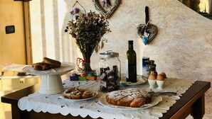 A table with pastries, a cake, a vase with dried flowers, and a bottle. - AGRITURISMO IL CARDO (Soiano del Lago)