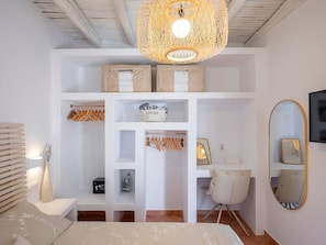 Ein Schlafzimmer mit Bett, Schreibtisch, Stuhl, Kleiderschrank, Spiegel und einer Pendelleuchte.