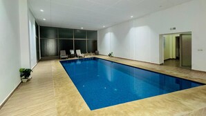 An indoor swimming pool with clear water, surrounded by white walls and a tiled floor. - Apartment in the center of Guéliz with swimming pool (Marrakesh)