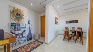 A dining area with a table, chairs, and a wall-mounted clock. - Apartment in the center of Guéliz with swimming pool (Marrakesh)