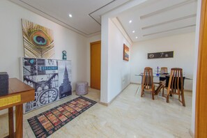 A dining area with a table, chairs, and a wall-mounted clock. - Apartment in the center of Guéliz with swimming pool (Marrakesh)