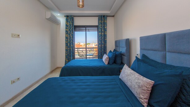 A room with two beds, a ceiling light, and a view through a window. - Apartment in the center of Guéliz with swimming pool (Marrakesh)