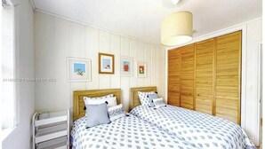 Ein Schlafzimmer mit zwei Betten, einem Holzschrank und gerahmten Bildern an der Wand.