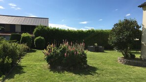 Un giardino curato con prato, piante fiorite e un'area salotto.