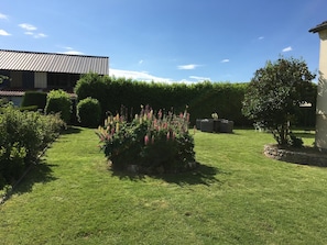 A well-maintained garden with a lawn, flowering plants, and a seating area. - At Tati Mag (Thiberville)