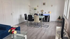 Un soggiorno moderno con un divano blu, un tavolino da caffè in vetro e un'area pranzo con un tavolo e sedie in vetro.