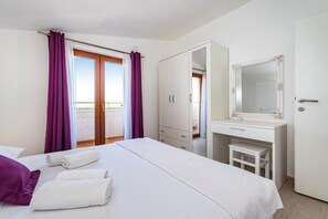 A hotel room with a bed, a desk, a wardrobe, and a balcony with purple curtains. - Holiday Home Tonka with pool (Donje Raštane)