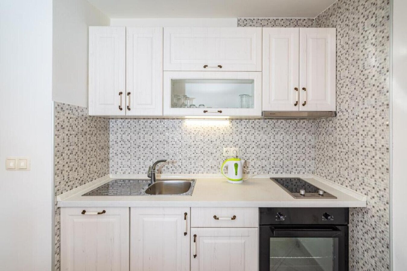 A kitchen with white cabinets, a microwave, a sink, and an oven.