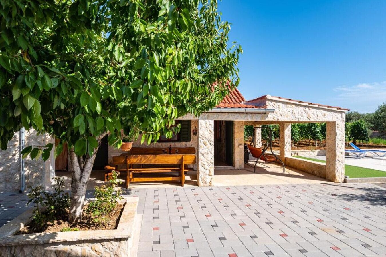 A stone building with a tiled patio, a wooden bench, and a hammock.