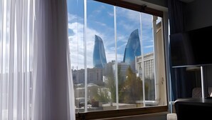 A room with a large window, a chair, and a TV. - Gold Senator Hotel (Baku)